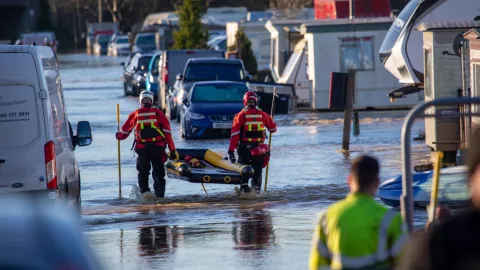 Two people holding a rescue boat and walking in a flooded area at Proctor's Park