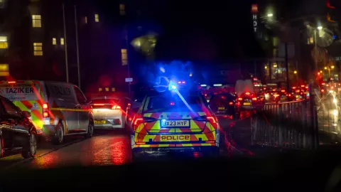 Police car driving with blue lights on a busy road